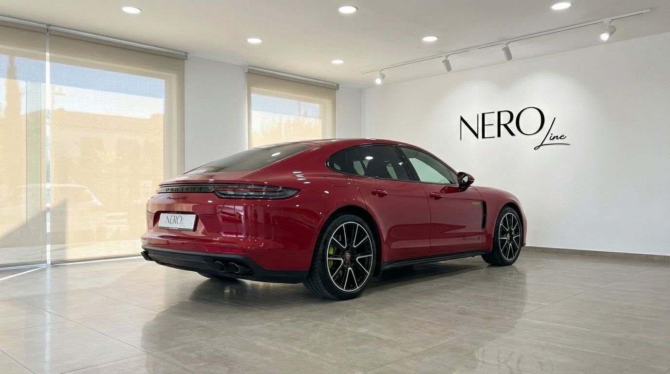 The racing red Porsche Panamera 4S Hybrid is showcased in a modern showroom, captured from its elegant rear three-quarter view.