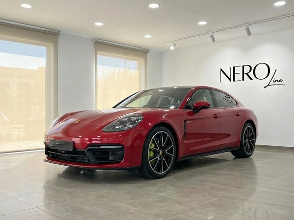 Porsche Panamera — Luxury Sedan in Alicante A racing red 2024 Porsche Panamera 4S Hybrid is parked in a showroom, viewed from the front three-quarter angle in Alicante.