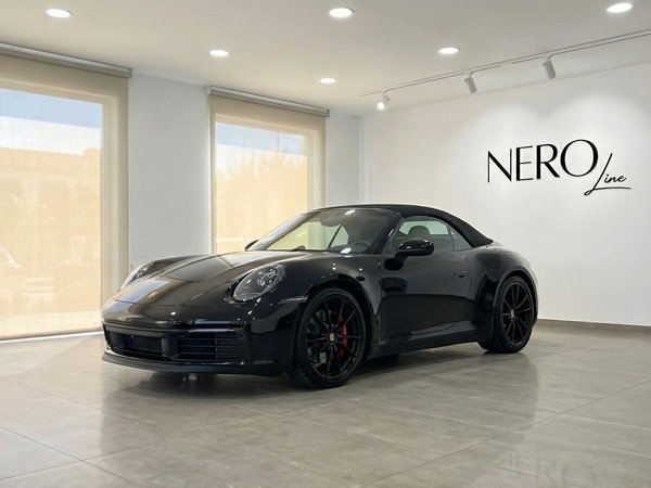 Porsche 911 Carrera S Cabrio — Showroom, Madrid Un Porsche 911 Carrera S Cabrio negro de 2023, visto desde un ángulo frontal tres cuartos, estacionado en un moderno showroom en Madrid.