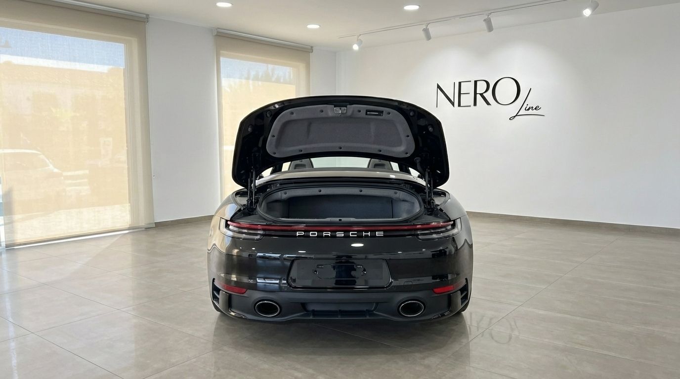 El Porsche 911 Carrera S Cabrio negro se muestra desde la parte trasera con el maletero abierto, estacionado en una sala de exposición en Madrid.