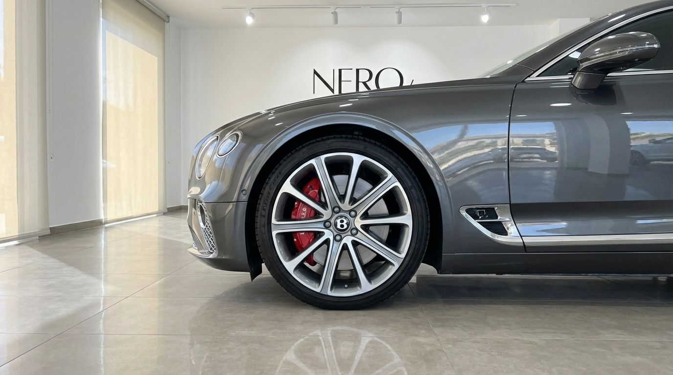 The gunmetal gray Bentley Continental GT Speed V12 is showcased from its front-left side, highlighting the wheel with red calipers in Alicante.