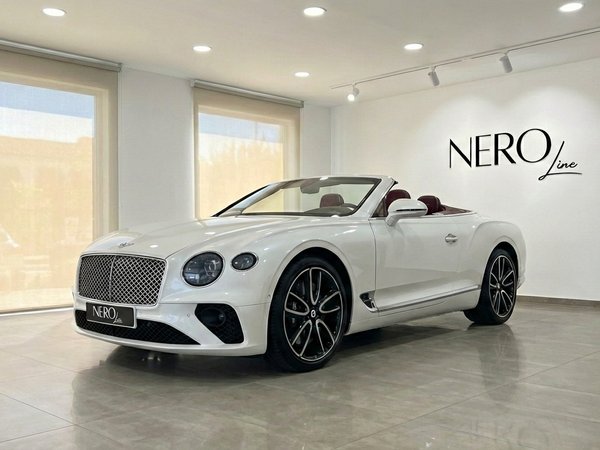 Bentley Continental GTC — Luxury convertible in Barcelona The pearl white 2020 Bentley Continental GTC convertible, with its top down and red interior, is showcased in a Barcelona showroom.