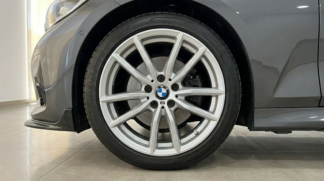 The front alloy wheel and tire of a grey BMW 320d are prominently displayed, with part of the car's body visible, in Alicante.