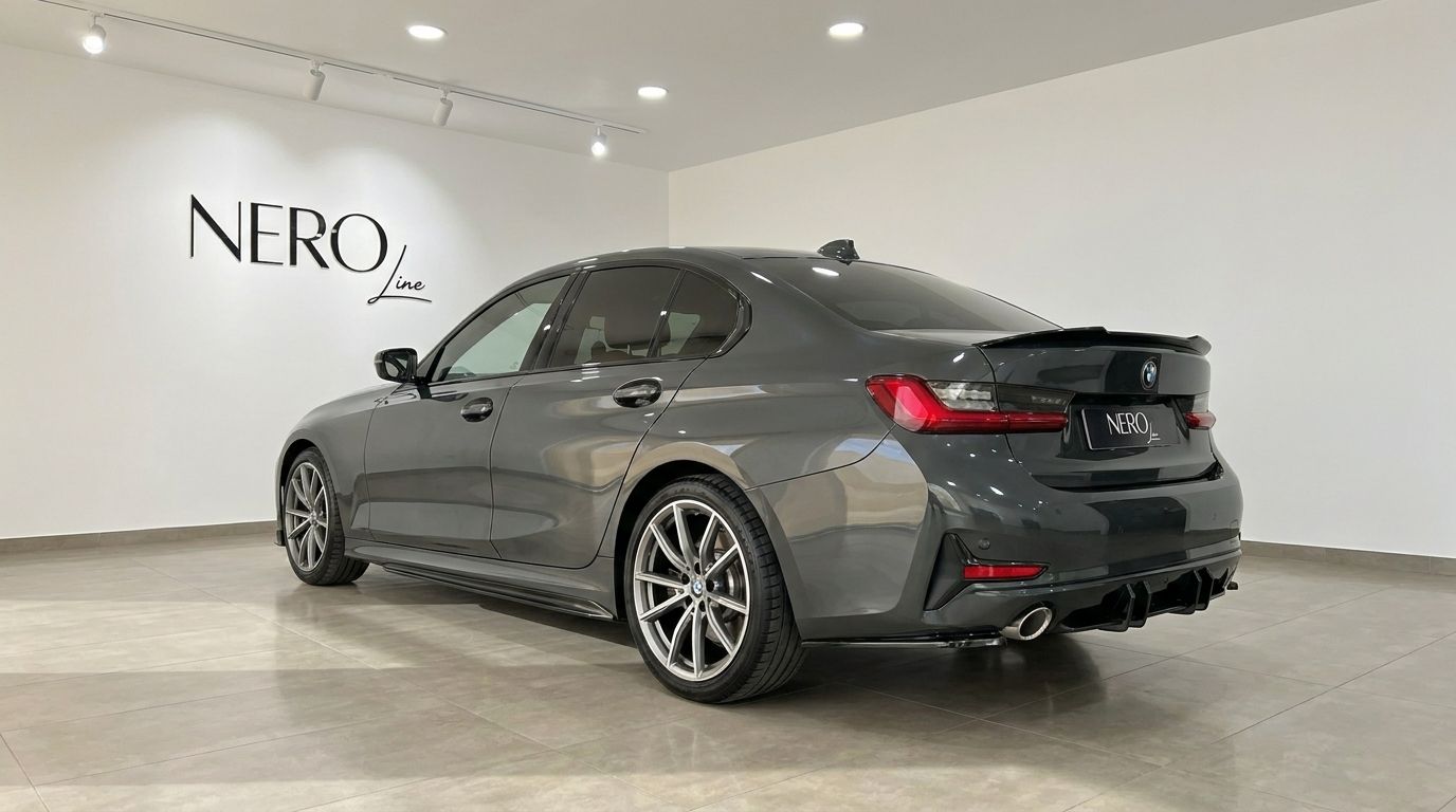 The dark grey 2024 BMW 320d is shown from a rear three-quarter angle in a bright showroom in Alicante, featuring the NEROline logo on the wall.