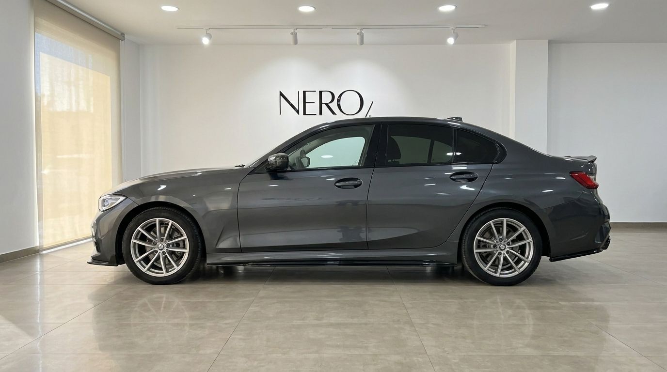 The grey 2024 BMW 320d luxury sedan is shown from its side profile, parked indoors at the Nero-Line showroom in Alicante.