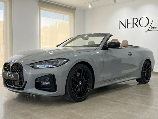 BMW 420d Cabriolet — Front three-quarter view The metallic Brooklyn Grey BMW 420d Cabriolet, with its top down and tan interior, is showcased in a Marbella showroom.