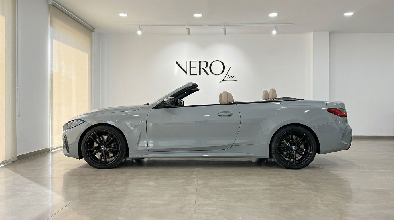 The metallic Brooklyn Grey BMW 420d Cabriolet, with its top down and beige interior, is parked in a showroom in Marbella.