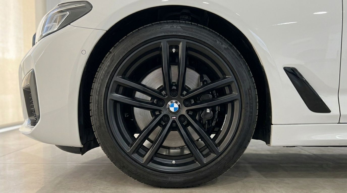 The front wheel of the white BMW 530e xDrive, featuring a black multi-spoke rim and visible brake disc, in Alicante.