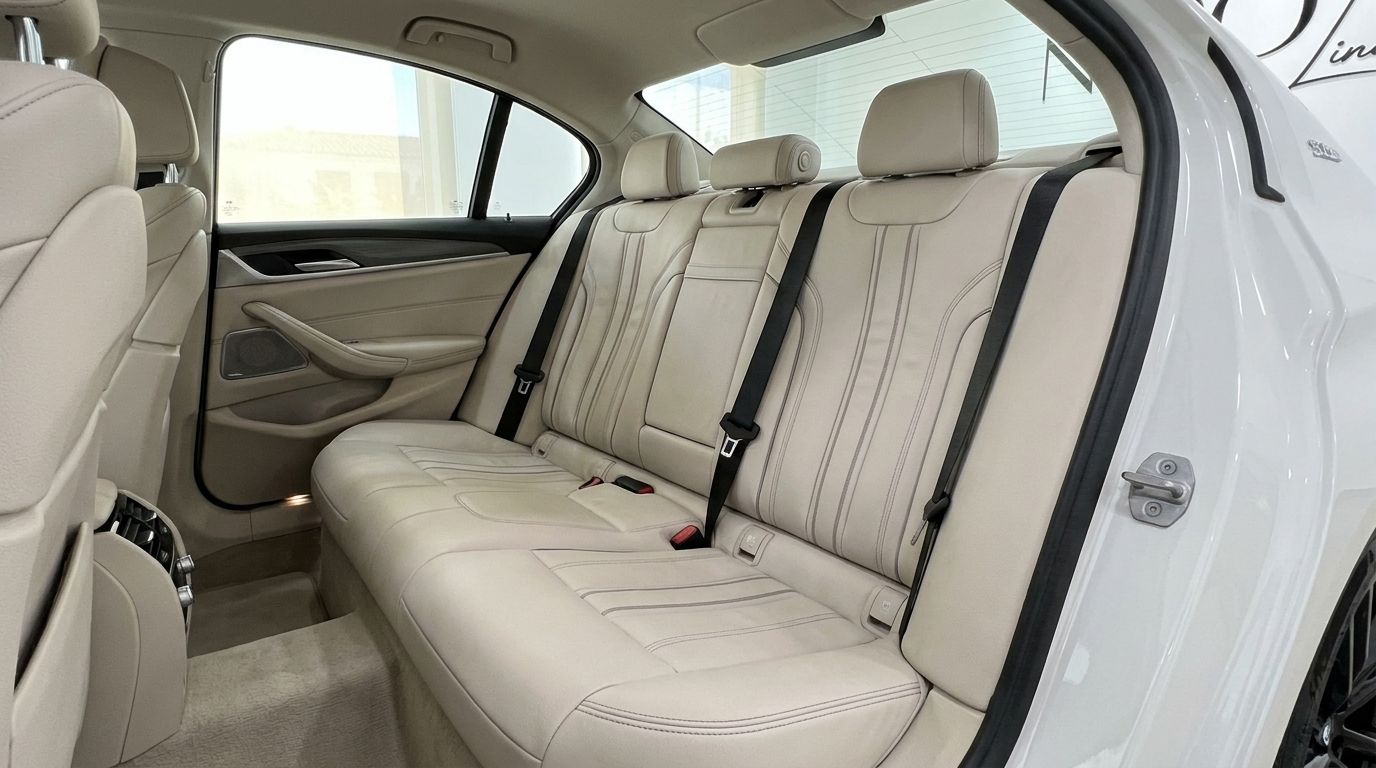 The luxurious rear passenger seats of the BMW 530e xDrive in Alicante feature elegant light cream leather upholstery.