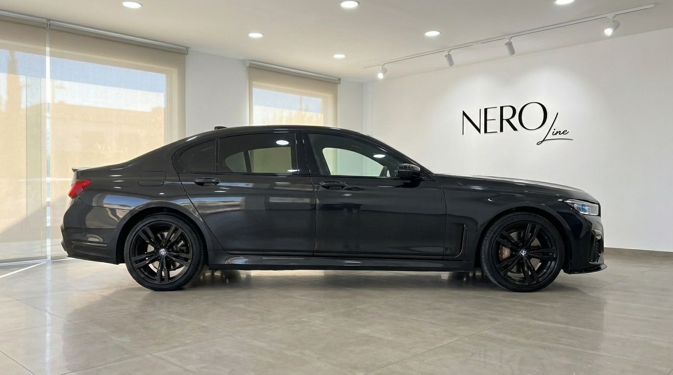 The sleek black BMW 730 luxury sedan is showcased from its side profile in a bright Alicante showroom.