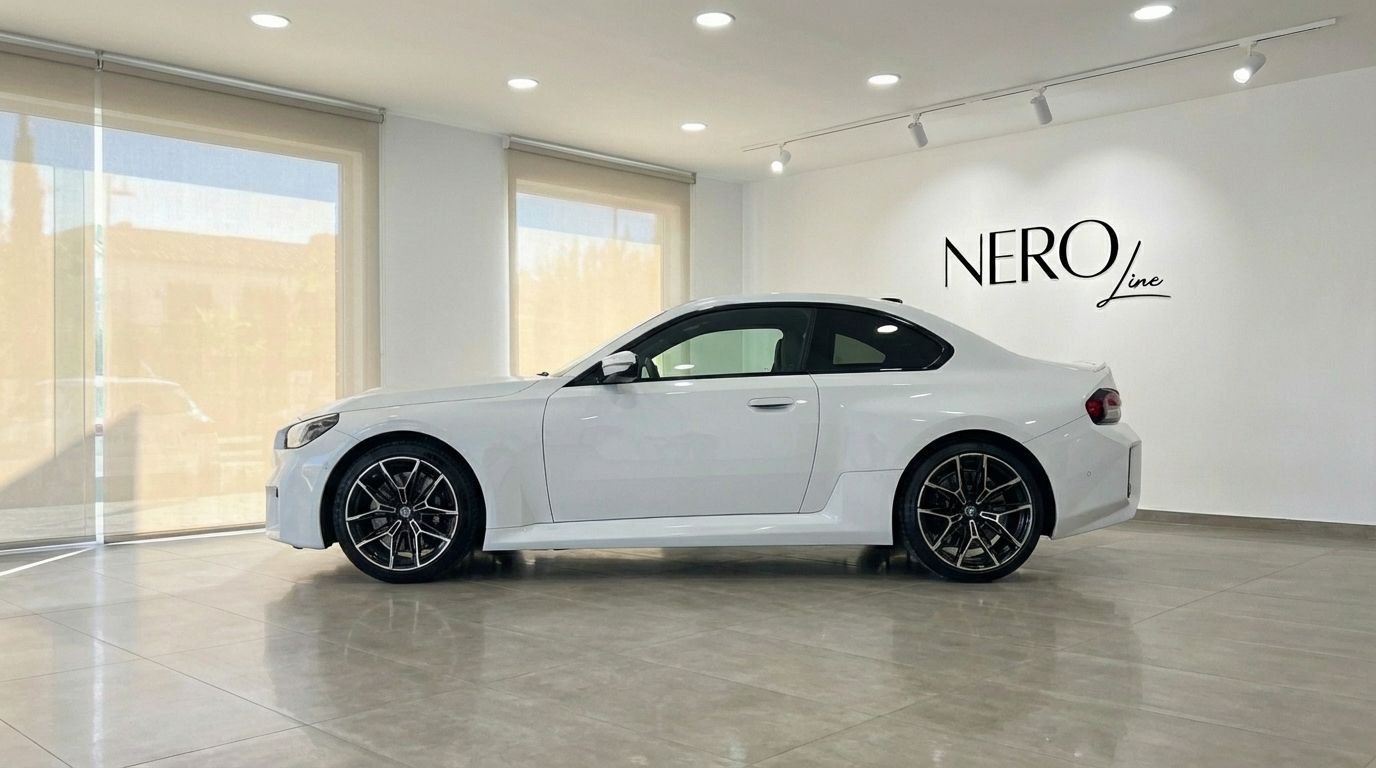 El BMW M2 Competition blanco de 2025 se exhibe de perfil en un moderno showroom en Madrid.