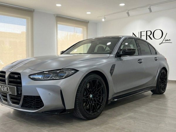 BMW M3 Competition xDrive — Marbella Showroom The 2023 BMW M3 Competition xDrive in Matte Frozen Pure Grey, shown from a front three-quarter view in a Marbella showroom.