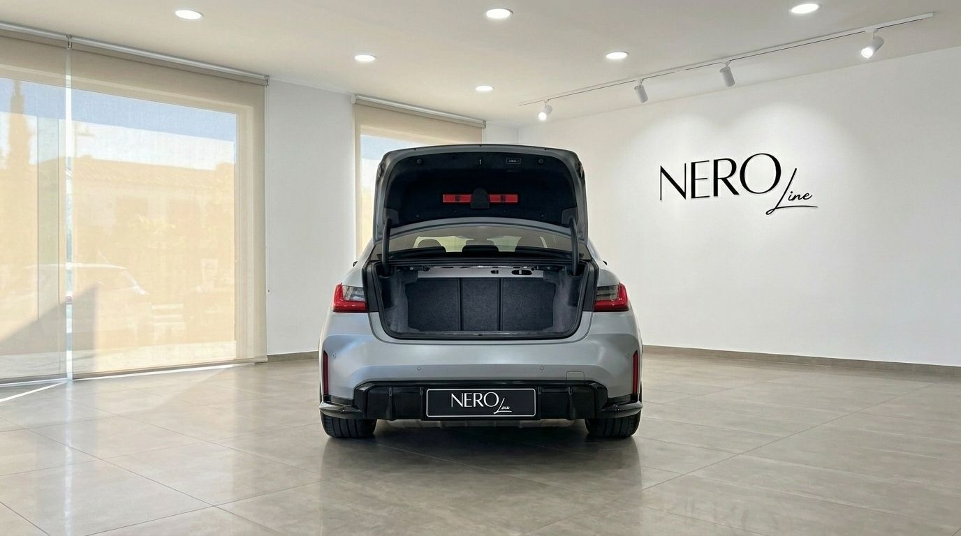 The rear view of the Matte Frozen Pure Grey BMW M3 Competition xDrive in Marbella, showcasing its spacious open trunk in a showroom.