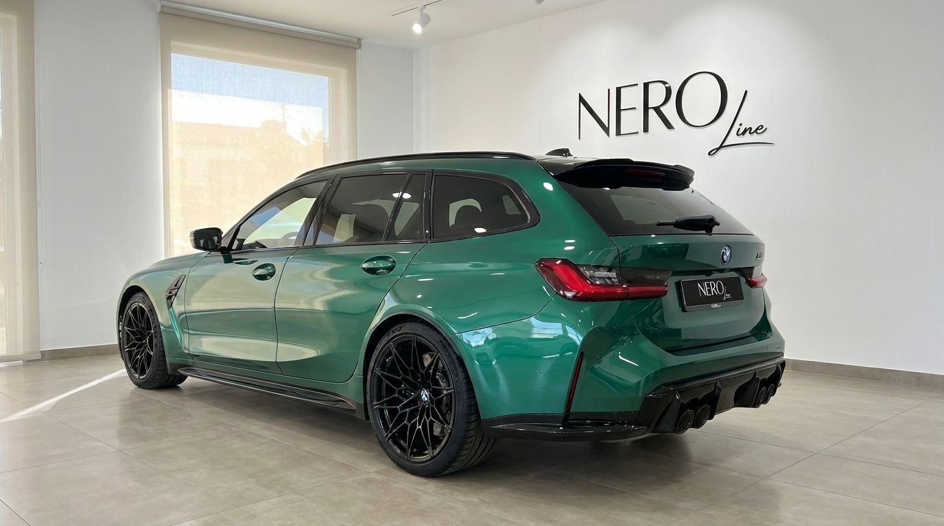 The metallic Isle of Man Green BMW M3 Touring Competition xDrive is parked in a bright showroom in Marbella, showcasing its rear three-quarter view.