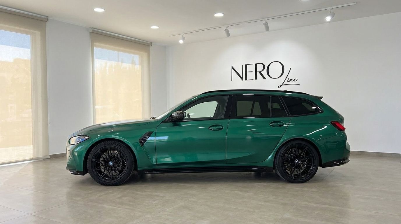 The metallic Isle of Man Green BMW M3 Touring Competition xDrive is showcased from a side view in a modern Marbella showroom.