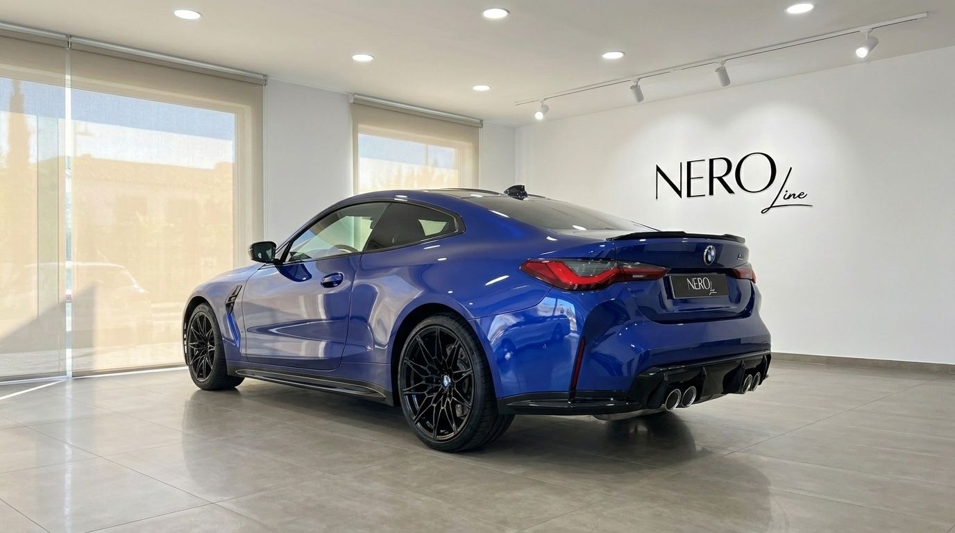 El BMW M4 Competition 2022 azul metálico se exhibe desde un ángulo trasero tres cuartos en una moderna sala de exposición en Madrid.