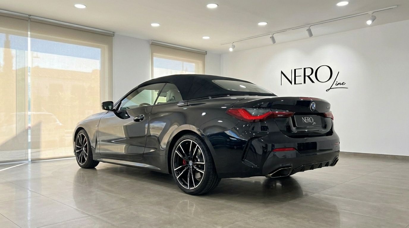 El BMW M440i Cabrio negro de 2023 se muestra desde un ángulo trasero tres cuartos con la capota puesta en un concesionario de Madrid.