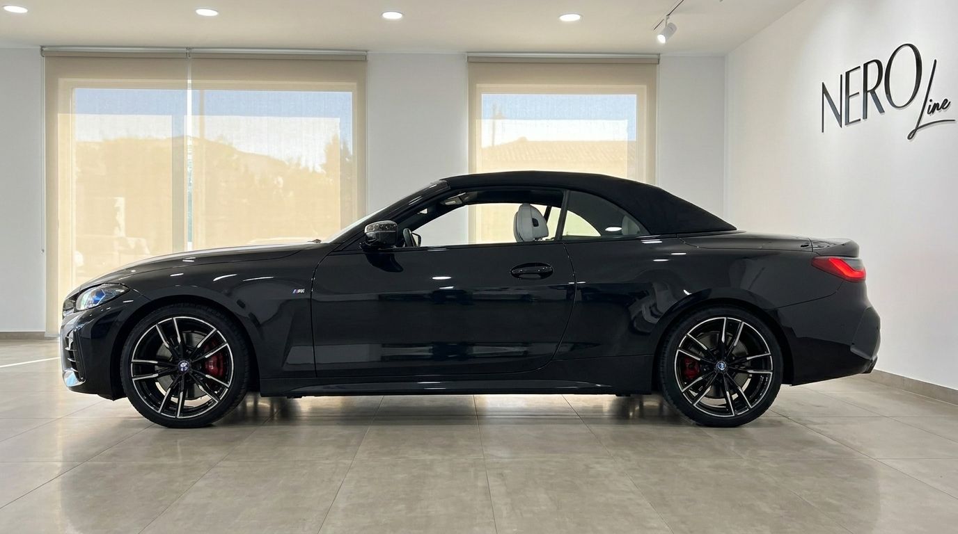 El BMW M440i Cabrio negro se muestra de perfil con la capota de lona puesta, aparcado en un concesionario en Madrid.