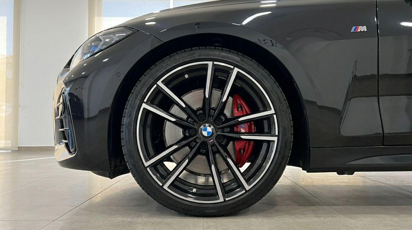 Primer plano de la rueda delantera del BMW M440i Cabrio negro brillante, mostrando una llanta multirradio negra con pinza de freno roja en Madrid.