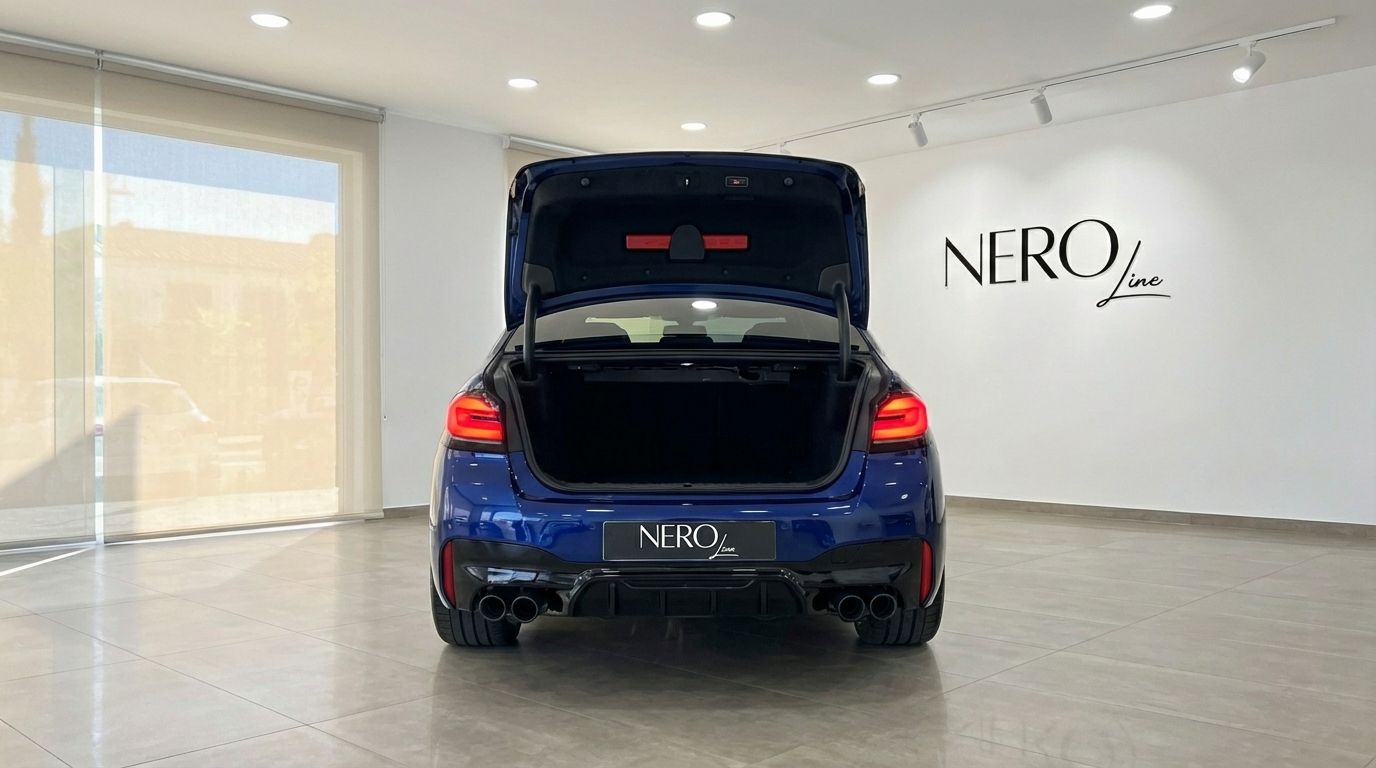 The metallic dark blue BMW M5 Competition Hybrid is shown from the rear with its trunk open in a Marbella showroom.