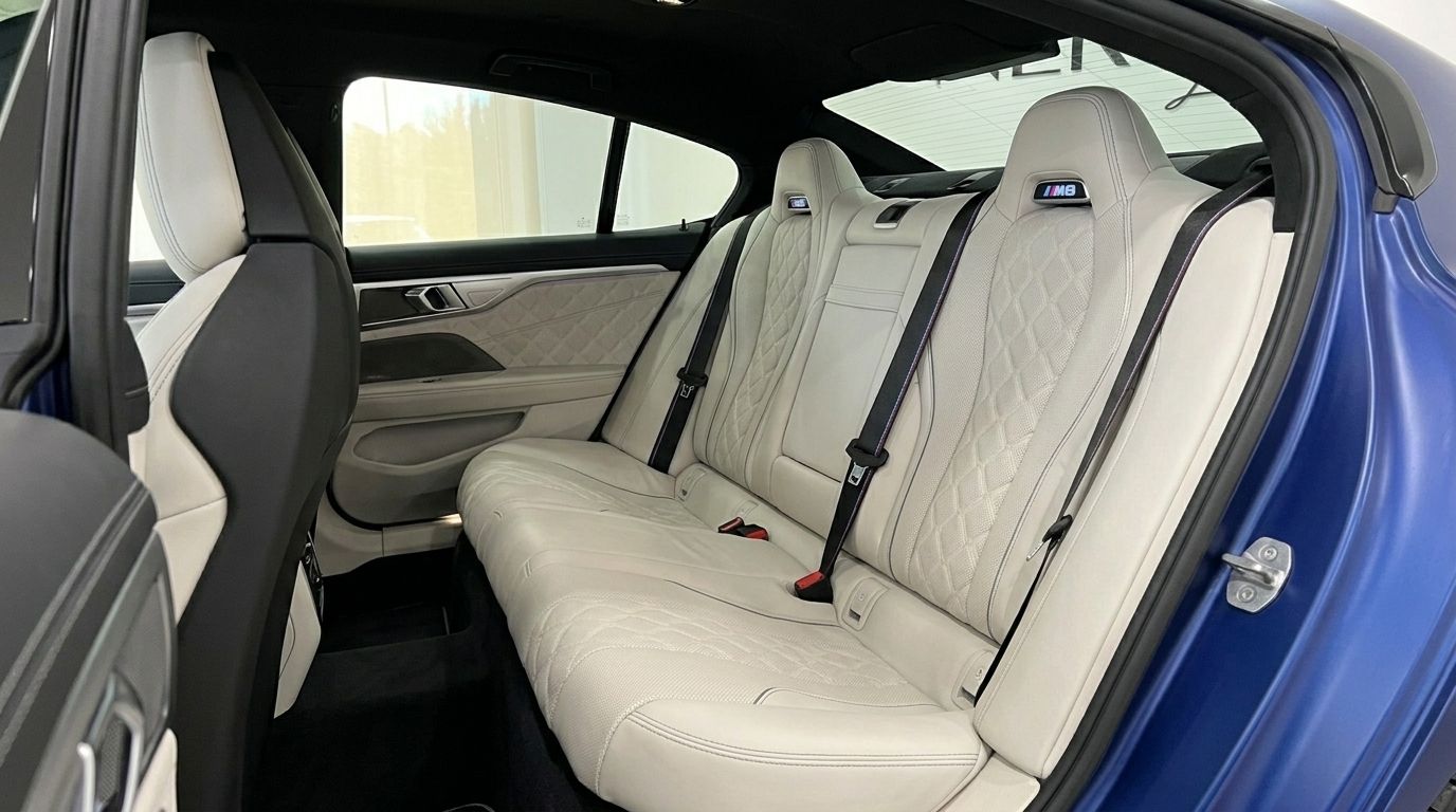 The luxurious rear seats of the BMW M8 Competition Gran Coupe in Marbella, featuring quilted white leather upholstery.