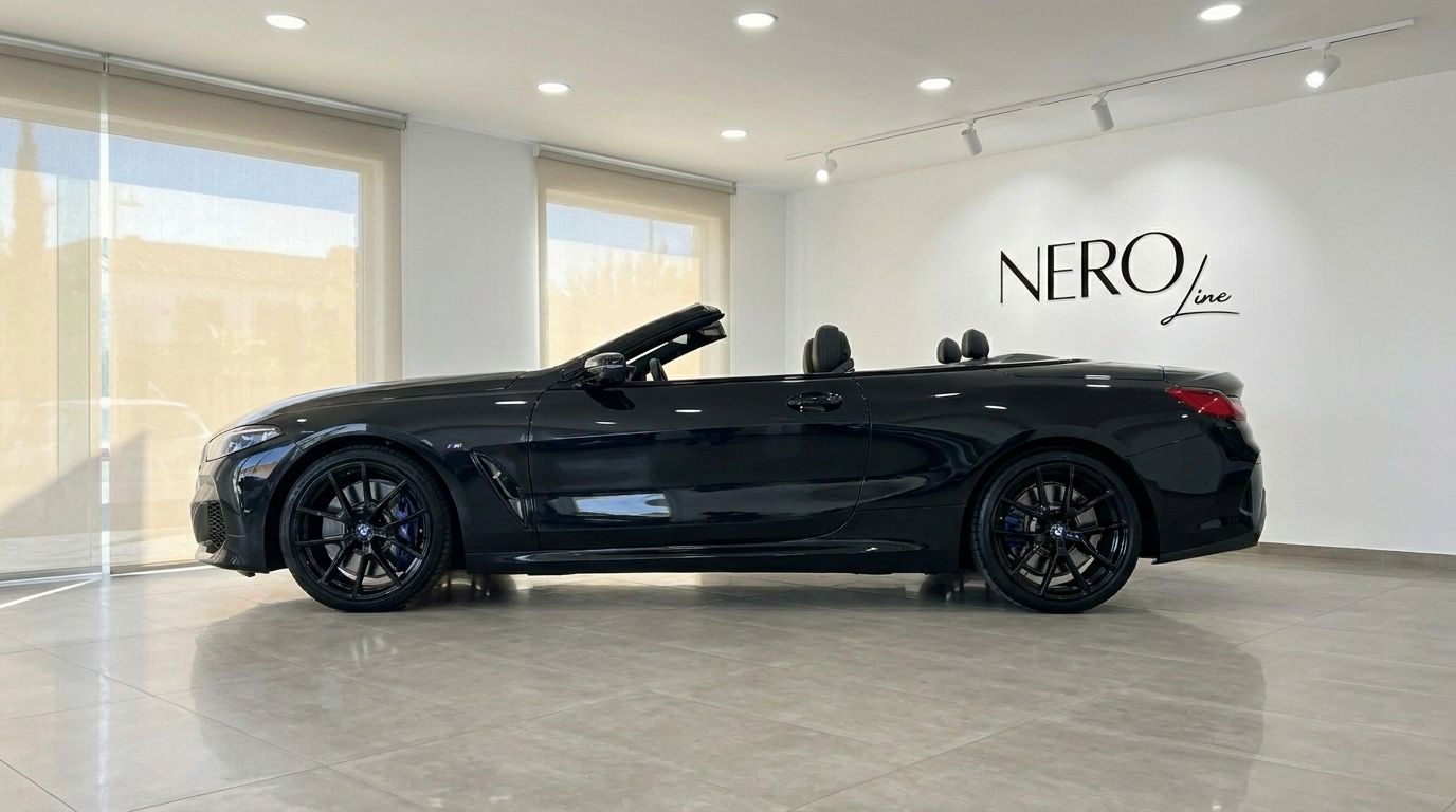 The black 2021 BMW M850 convertible, with its top down, is showcased from a side profile in a bright Alicante showroom.