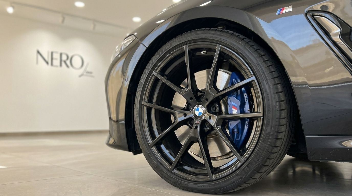 Close-up of the 2021 BMW M850's gloss black front wheel, blue M Sport brake caliper, and fender in Alicante.