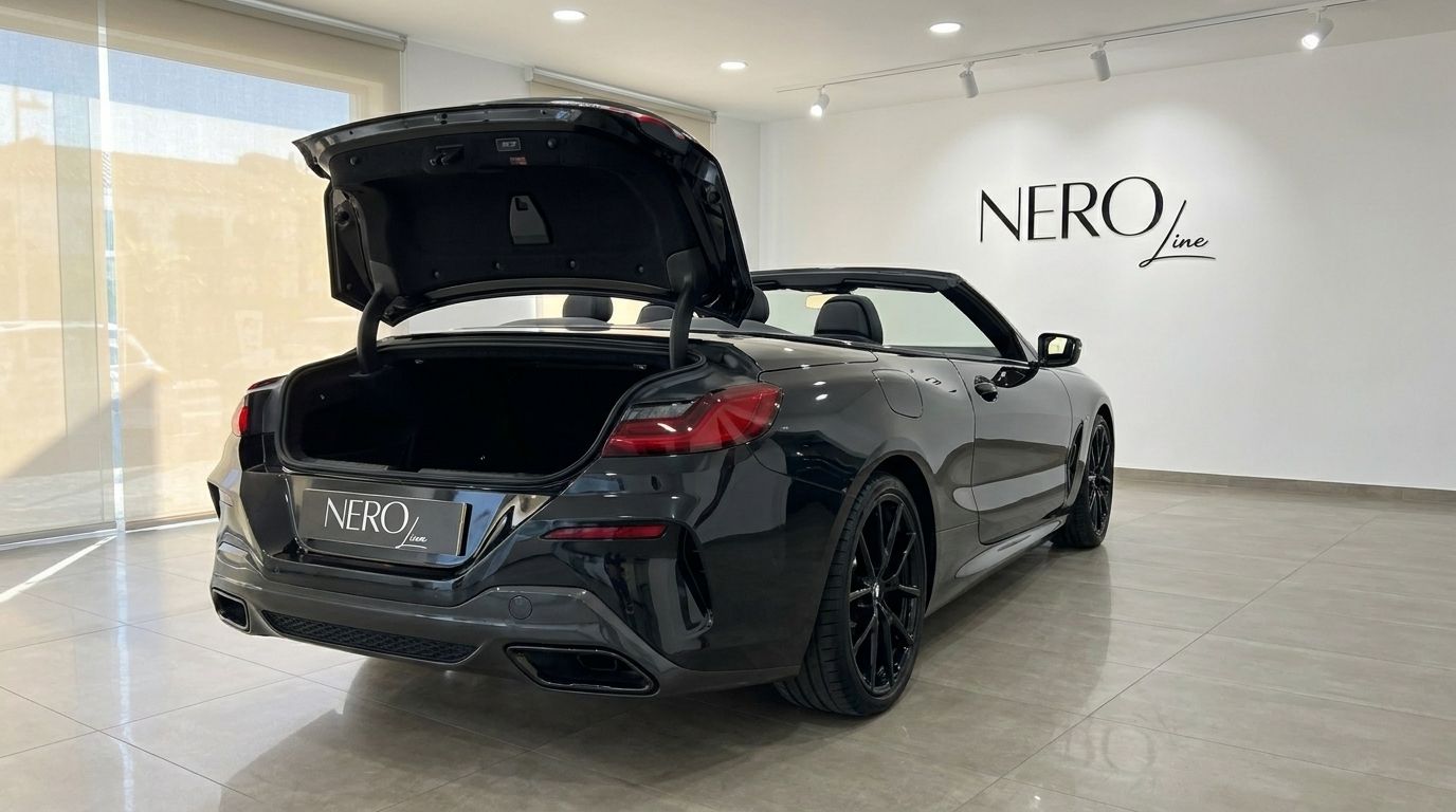 The black 2021 BMW M850 convertible is shown from the rear with its trunk open, parked in a showroom in Alicante.