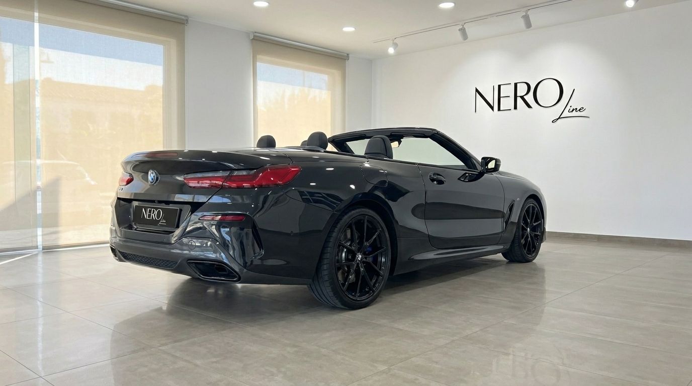 The sleek black 2021 BMW M850 convertible is parked indoors, showcasing its rear three-quarter view with the top down in Alicante.