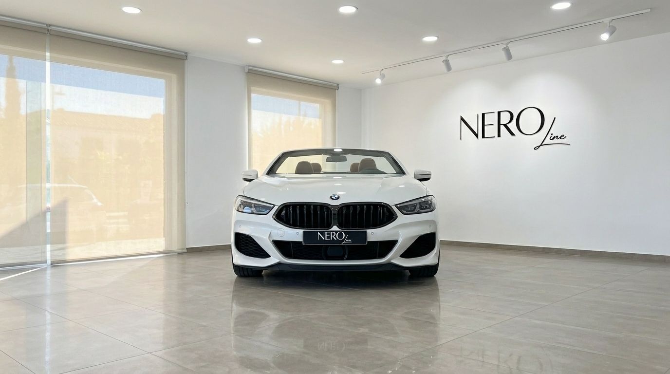 The white 2024 BMW M850i Cabriolet convertible is parked head-on in a bright showroom in Alicante, featuring the NEROline logo.