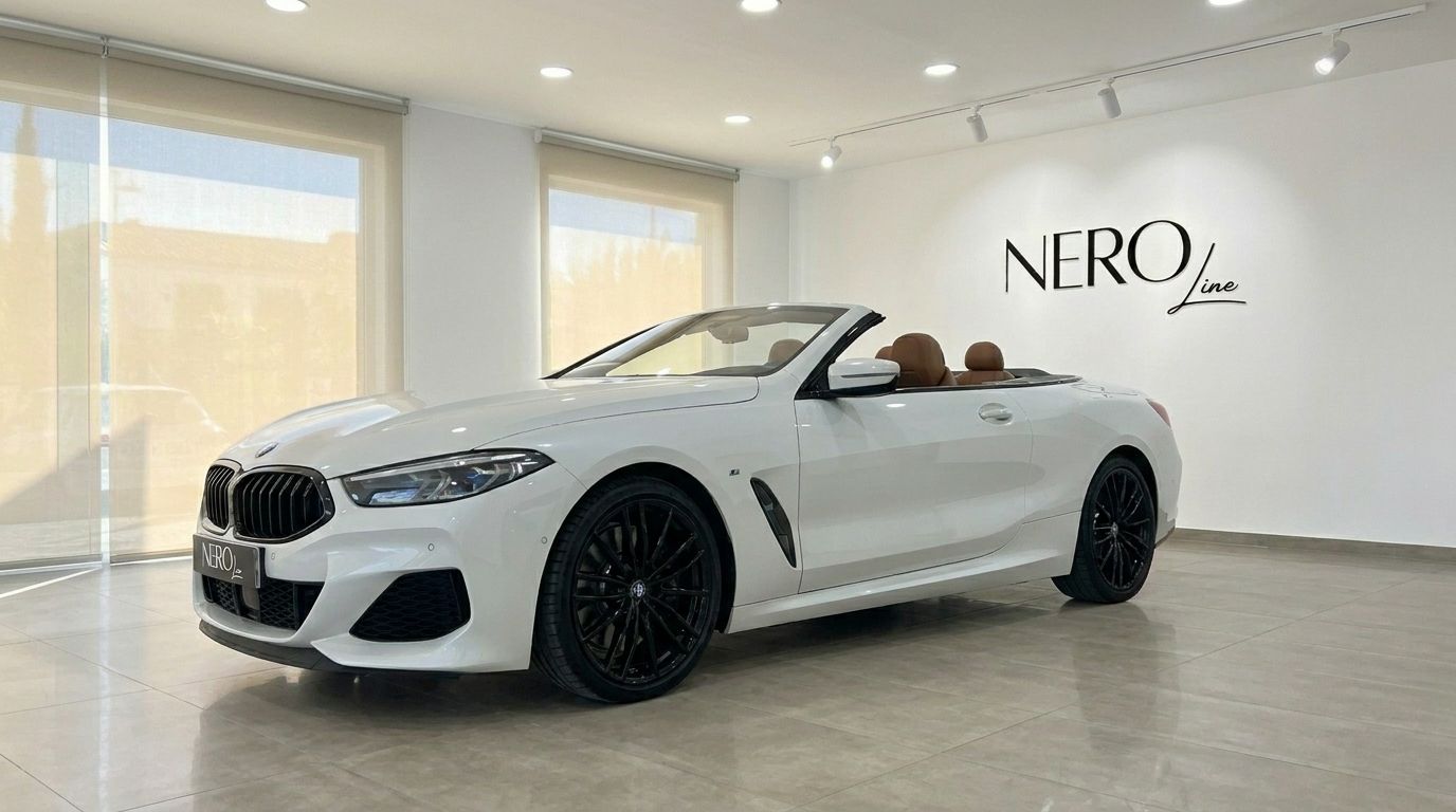 The white BMW M850i Cabriolet, with its convertible top down and luxurious brown interior, is elegantly displayed in a showroom in Alicante.