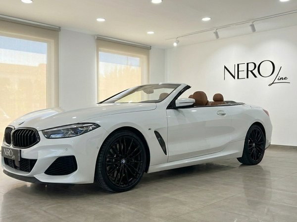 BMW M850i Cabriolet — Luxury convertible in Alicante The white BMW M850i Cabriolet, with its convertible top down and luxurious brown interior, is elegantly displayed in a showroom in Alicante.