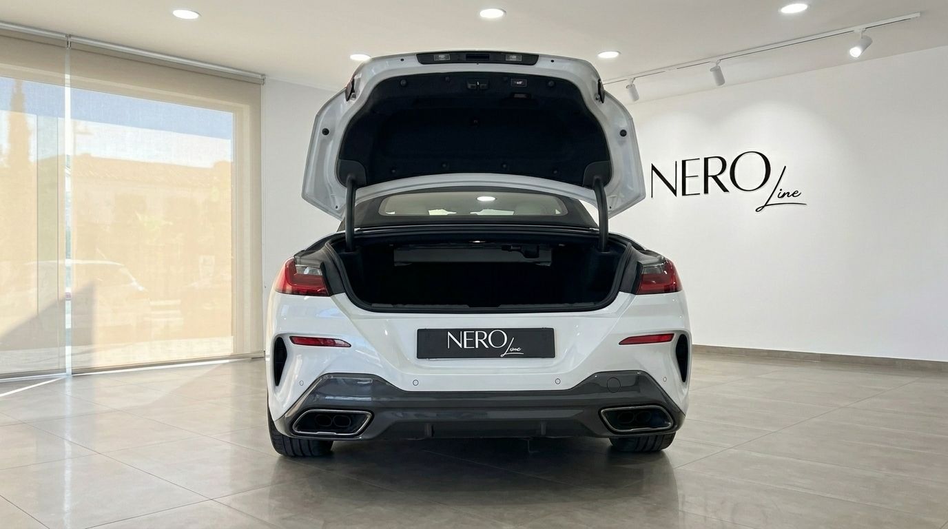 The white 2024 BMW M850i Cabriolet is seen from the rear with its trunk open in Alicante.