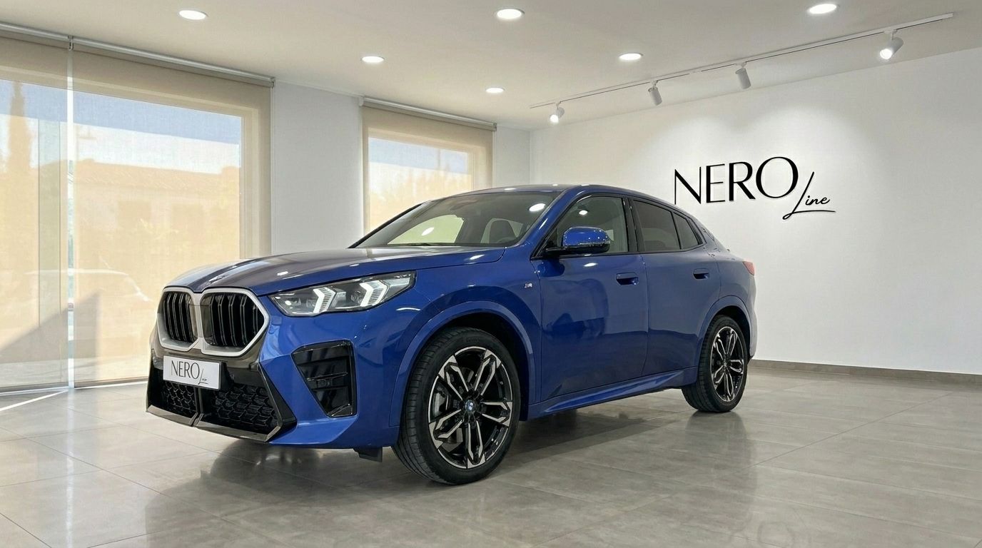 The blue 2025 BMW X2 is prominently displayed in a showroom, captured from a front three-quarter angle in Alicante.