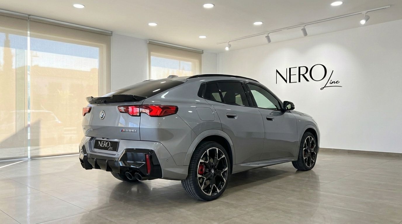 The 2024 BMW X2 M35i xDrive in gloss metallic grey, showcasing its sporty rear three-quarter view inside a showroom in Marbella.