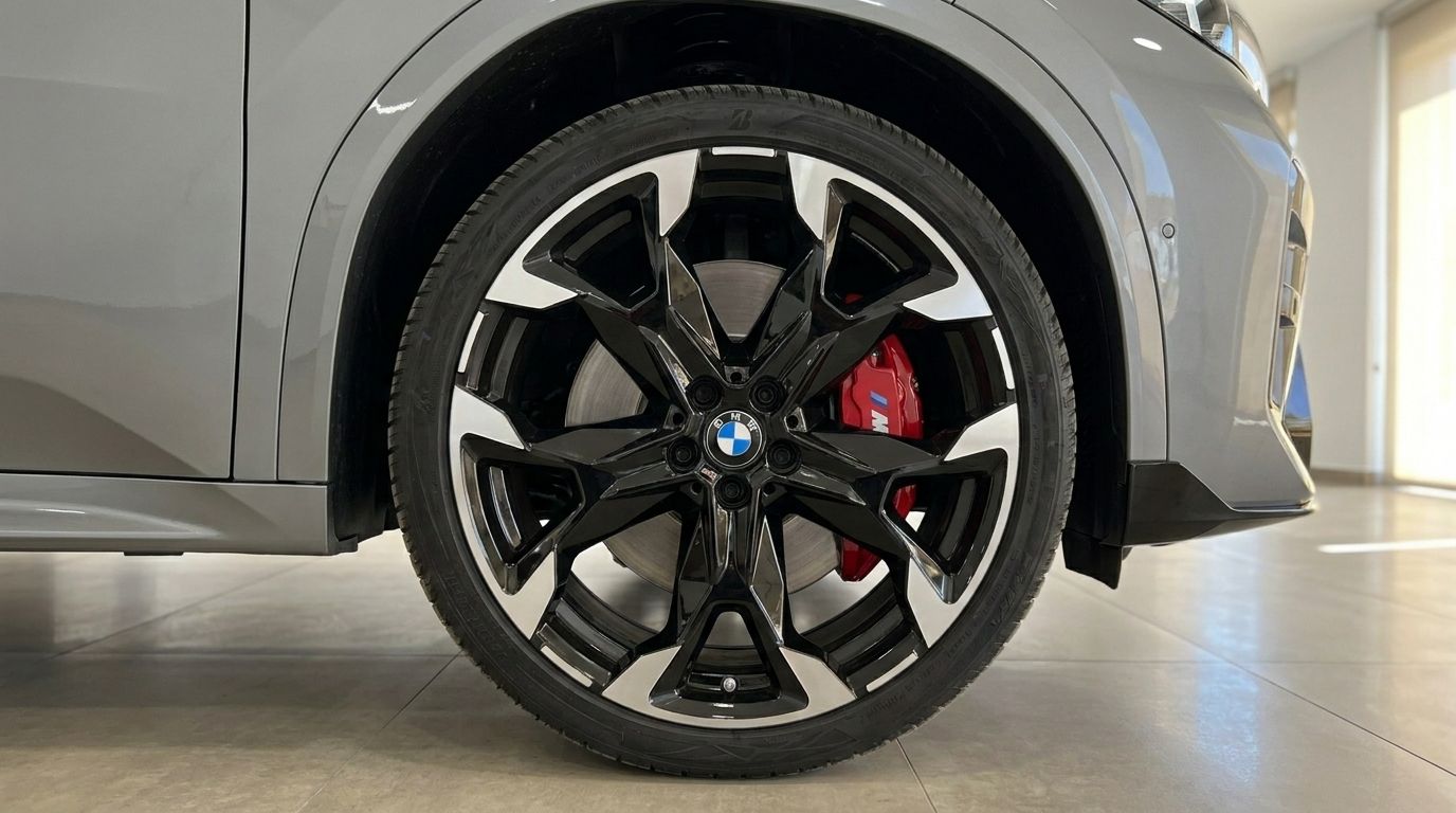The front wheel of the 2024 BMW X2 M35i xDrive, showcasing its black and silver multi-spoke rims and vibrant red M performance brake calipers in Marbella.