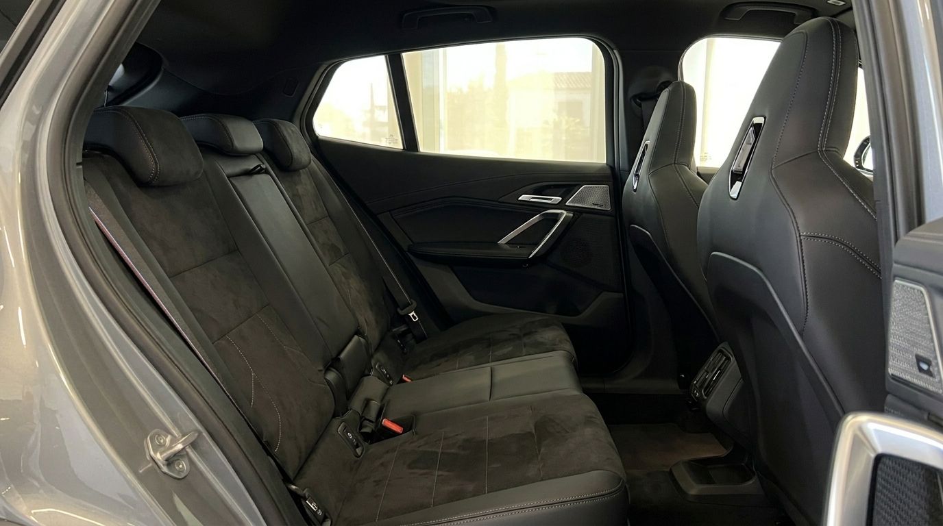 The image shows the luxurious rear interior of the BMW X2 M35i xDrive, featuring dark suede and leather seats in Marbella.