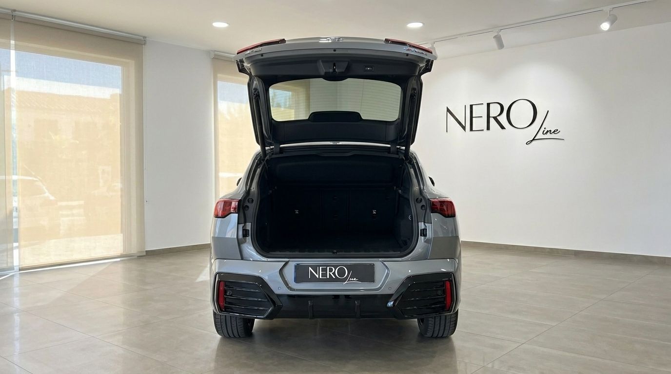The BMW X2 M35i xDrive is shown from the rear with its trunk open, revealing the spacious cargo area inside a Marbella showroom.