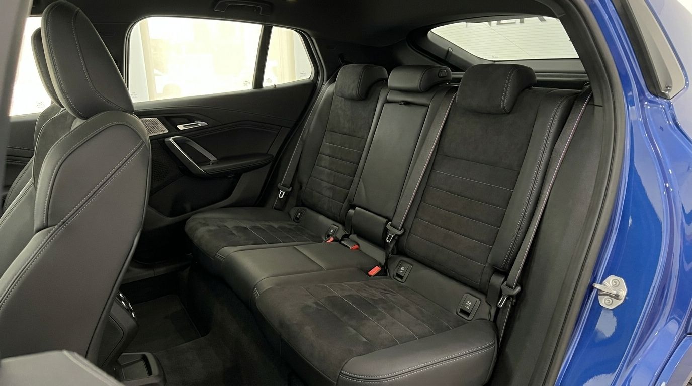 The luxurious rear interior seats of the 2025 BMW X2 are visible, showcasing dark upholstery and stitching in Alicante.