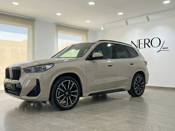 BMW X3 2.0 Diesel — Vordere Dreiviertelansicht Der glänzend beige BMW X3 2.0 Diesel wird in einer modernen Ausstellungshalle in Alicante aus der vorderen Dreiviertelansicht gezeigt.