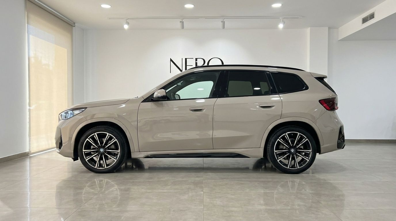 The gloss beige BMW X3 2.0 Diesel is showcased in a side profile view inside a showroom in Alicante.
