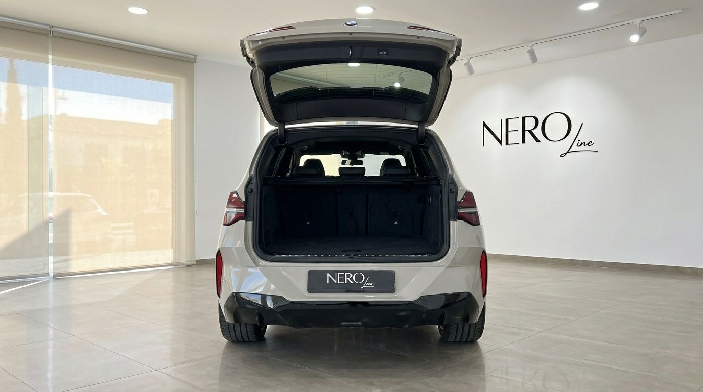 The rear view of the gloss beige BMW X3 2.0 Diesel, with its trunk open, displayed in a showroom in Alicante.