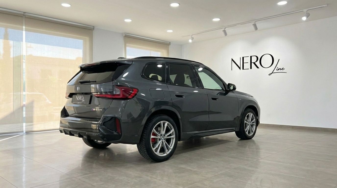 Il BMW X3 M50D xDrive 2026 grigio scuro è mostrato da un'angolazione posteriore a tre quarti in uno showroom ad Alicante, Spagna.