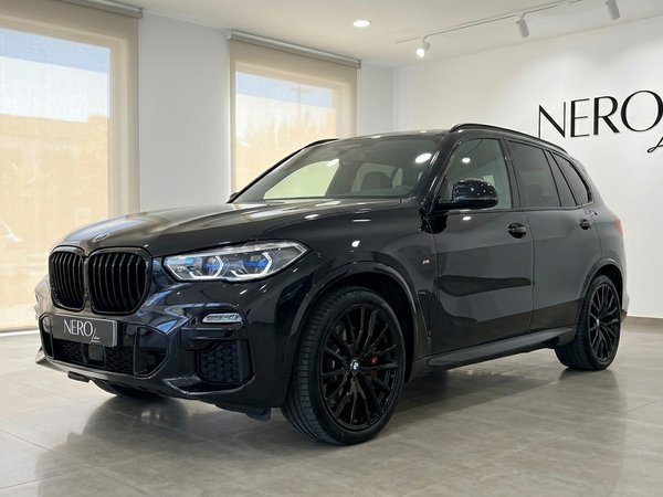 BMW X5 xDrive M Sport — Vue trois quarts avant Le BMW X5 xDrive M Sport noir est présenté sous un angle trois quarts avant dans un showroom moderne à Marbella.