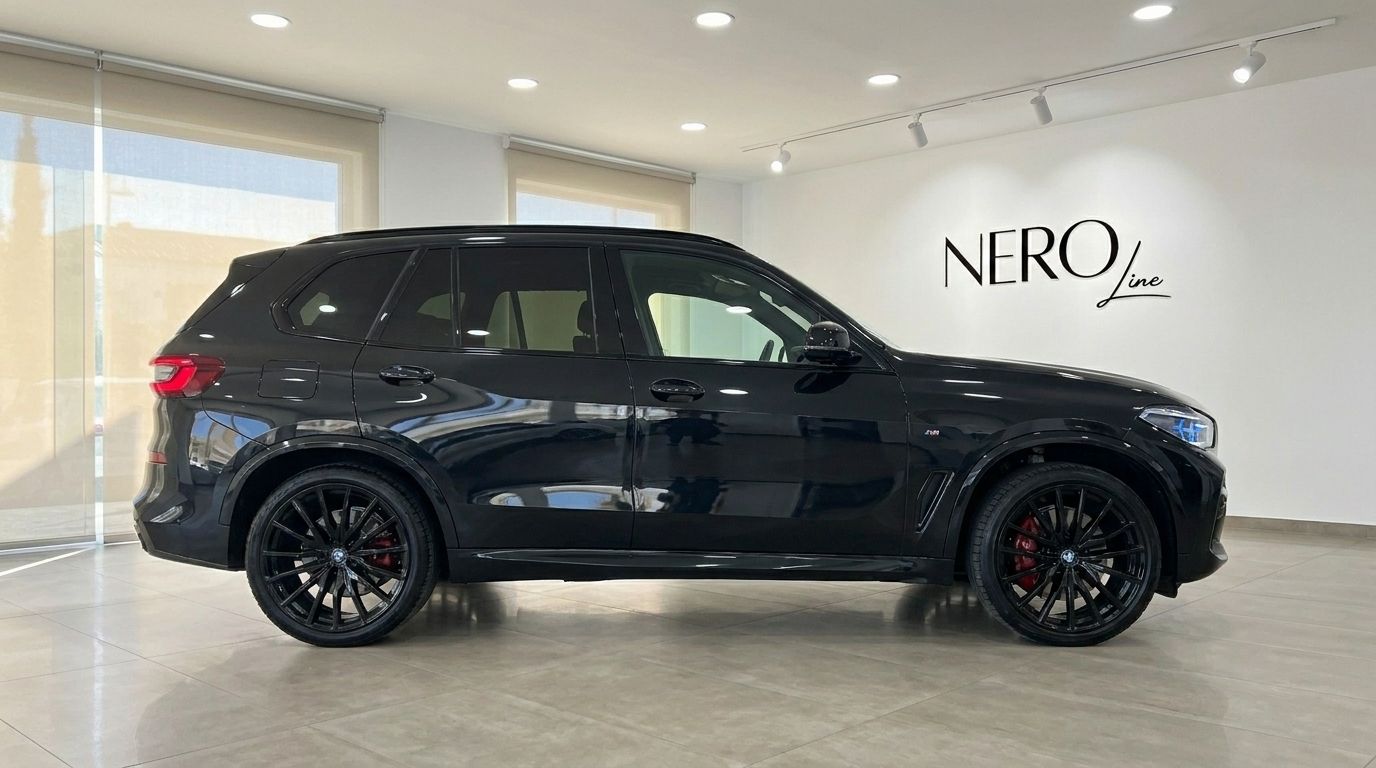 L'élégant BMW X5 xDrive M Sport noir de 2021 est présenté de profil dans un showroom de luxe à Marbella.