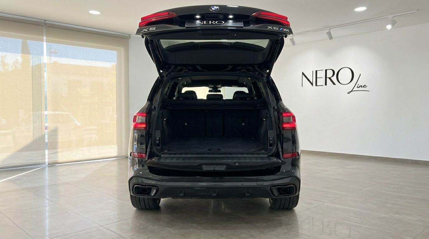 Le BMW X5 xDrive M Sport noir est présenté de l'arrière avec son coffre ouvert, soulignant son espace de chargement généreux à Marbella.