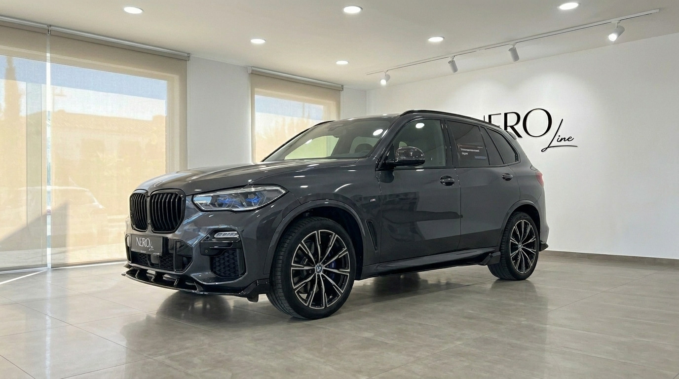 BMW X5 xDrive45e — Front three-quarter view The dark grey BMW X5 xDrive45e is showcased from a front three-quarter angle, parked indoors in Alicante.