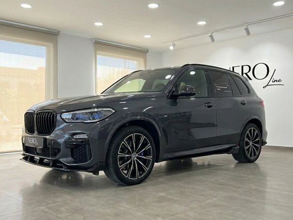 BMW X5 xDrive45e — Front three-quarter view The dark grey BMW X5 xDrive45e is showcased from a front three-quarter angle, parked indoors in Alicante.