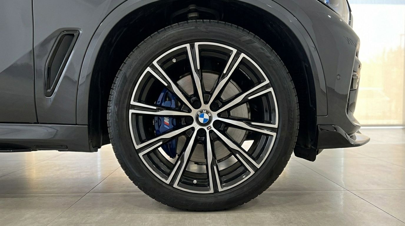 The BMW X5 xDrive45e's front wheel with its distinctive multi-spoke alloy rim and blue M Sport brake caliper, captured in Alicante.