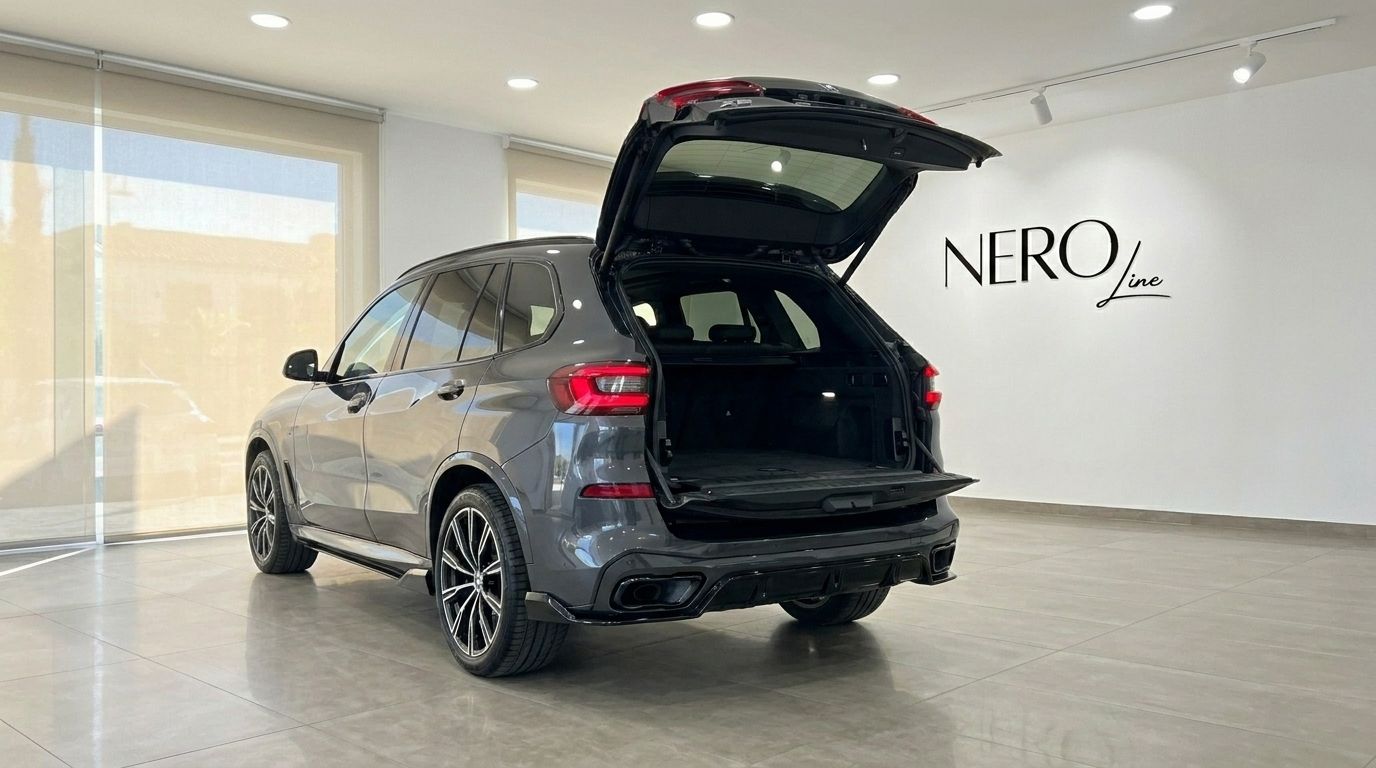 The dark grey BMW X5 xDrive45e is shown from the rear with its spacious trunk open in a showroom in Alicante.